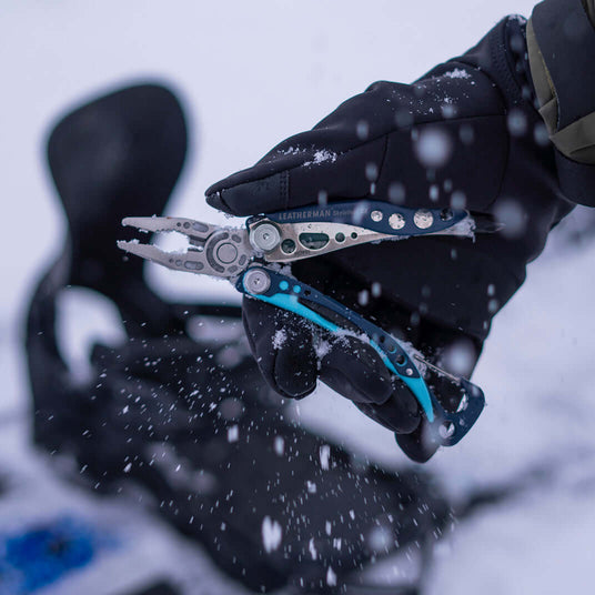Translation missing: en.Nightshade Leatherman Skeletool® CX pliers held in a gloved hand amidst falling snow in an outdoor setting