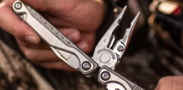 Outdoorsmen opening the pliers on the Leatherman Charge TTI  multi-tool.