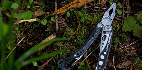 Leatherman Skeletool next to a set of gardening gloves on a wooden table