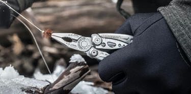 Fisherman using the pliers of Leatherman Skeletool multi-tool to attach fishing tackle to fishing line.