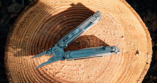 Leatherman FREE™ P4 with pliers open on a tree stump.