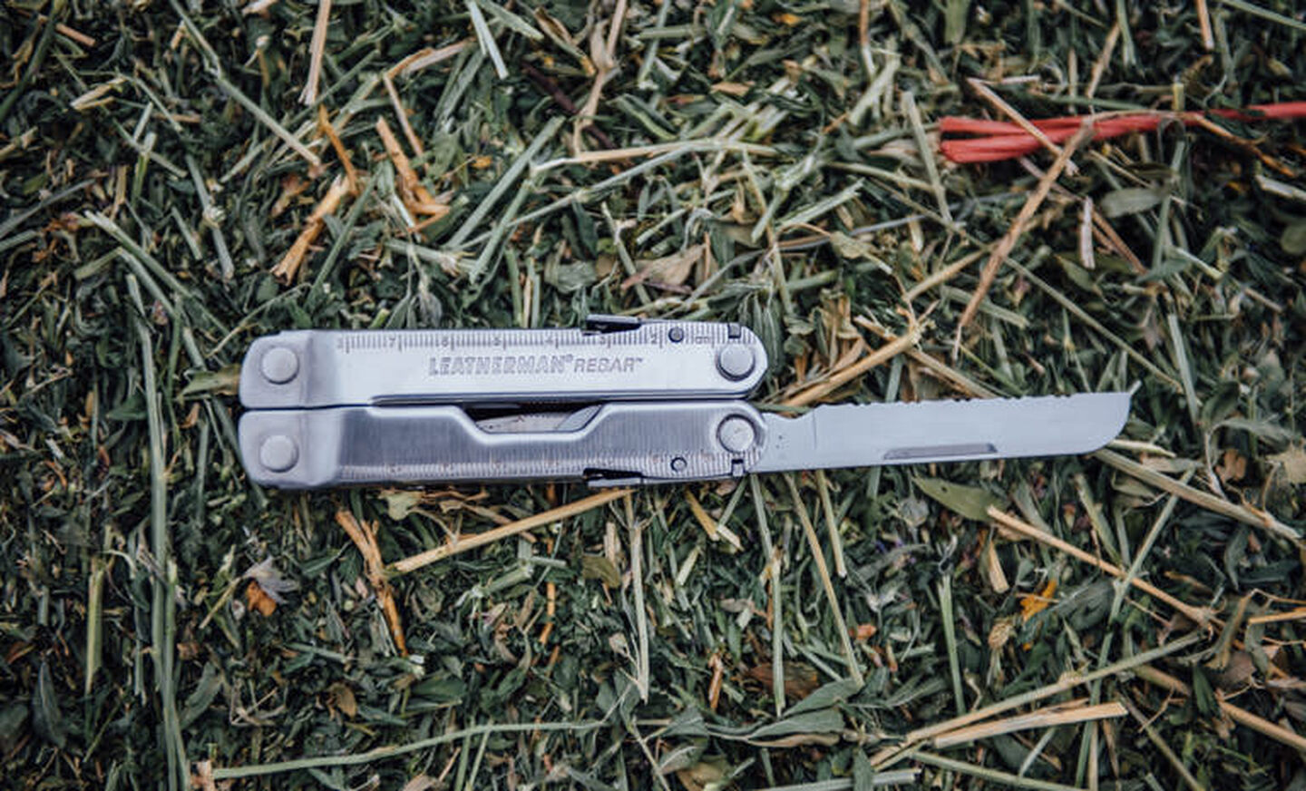Leatherman stainless steel heritage rebar multi-tool on grass, knife blade open