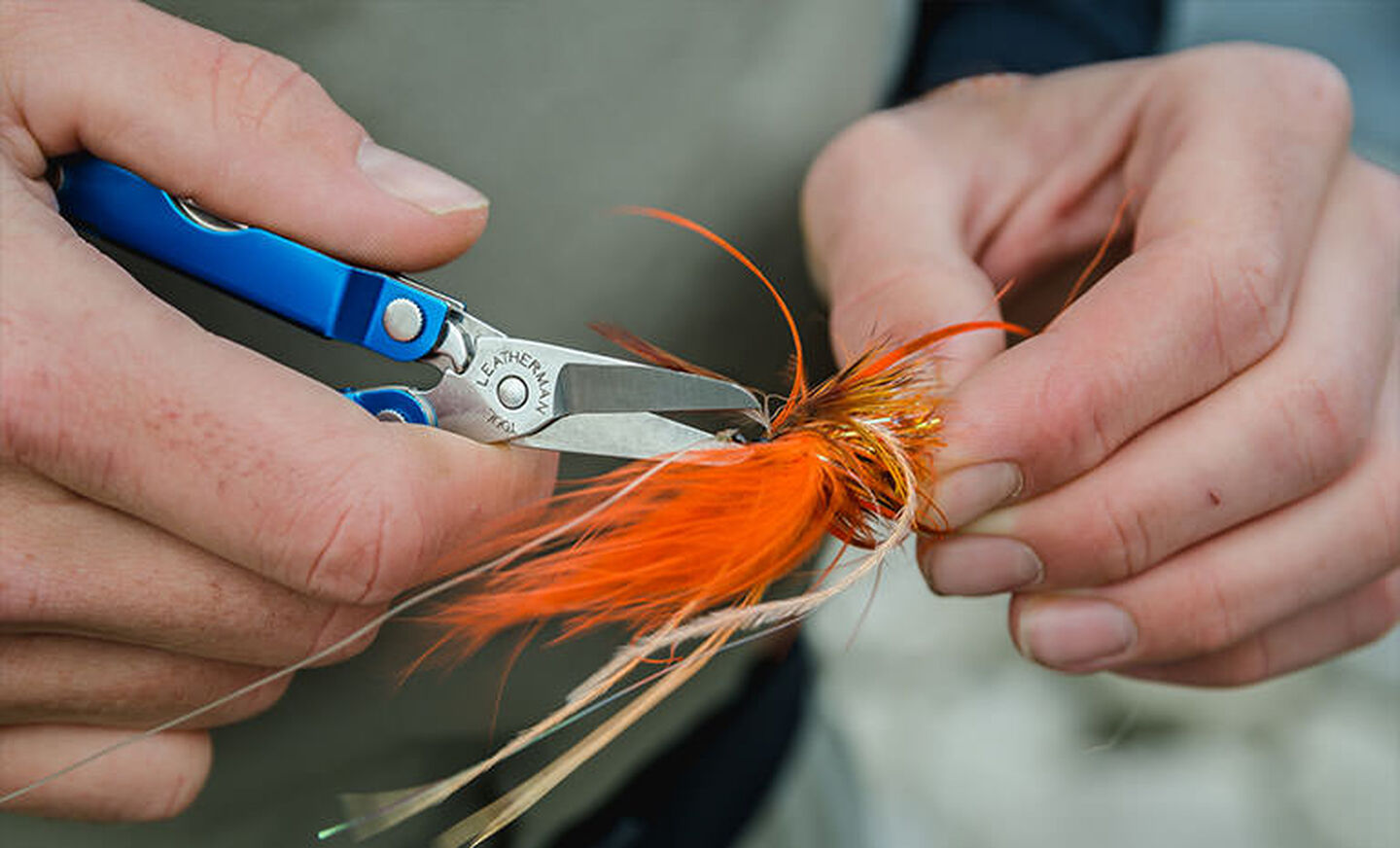 Man using blue Leatherman Micra to cut fishing line from fishing bait