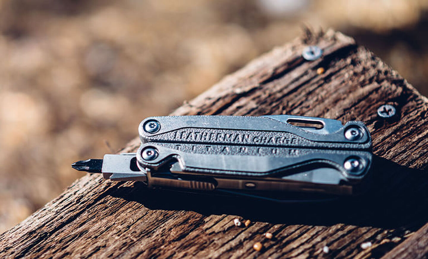 Leatherman Charge+ TTI laying on piece of wood under sunlight