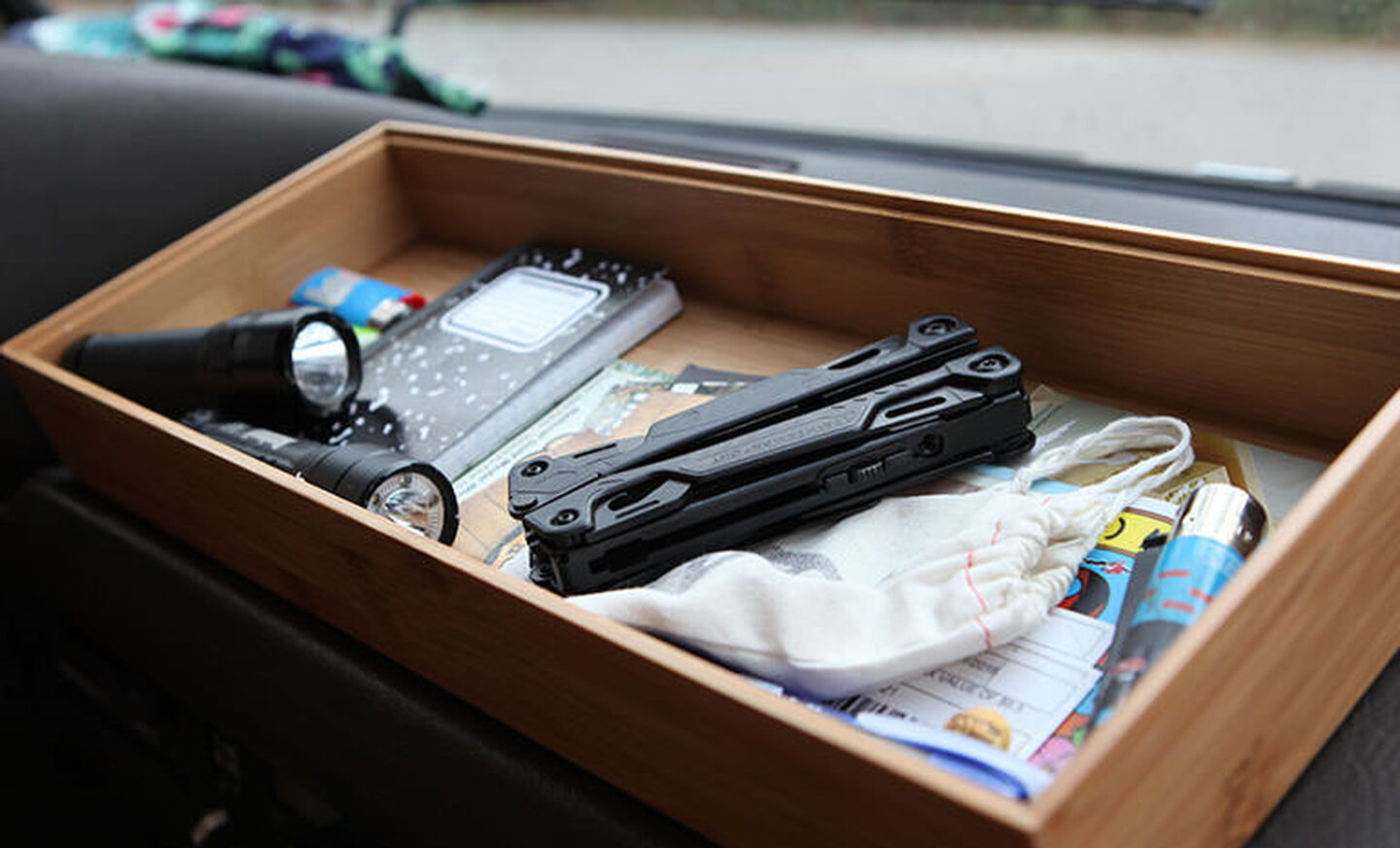 2 black flashlights, lined notebook, blue lighter, junk mail in wooden drawer  