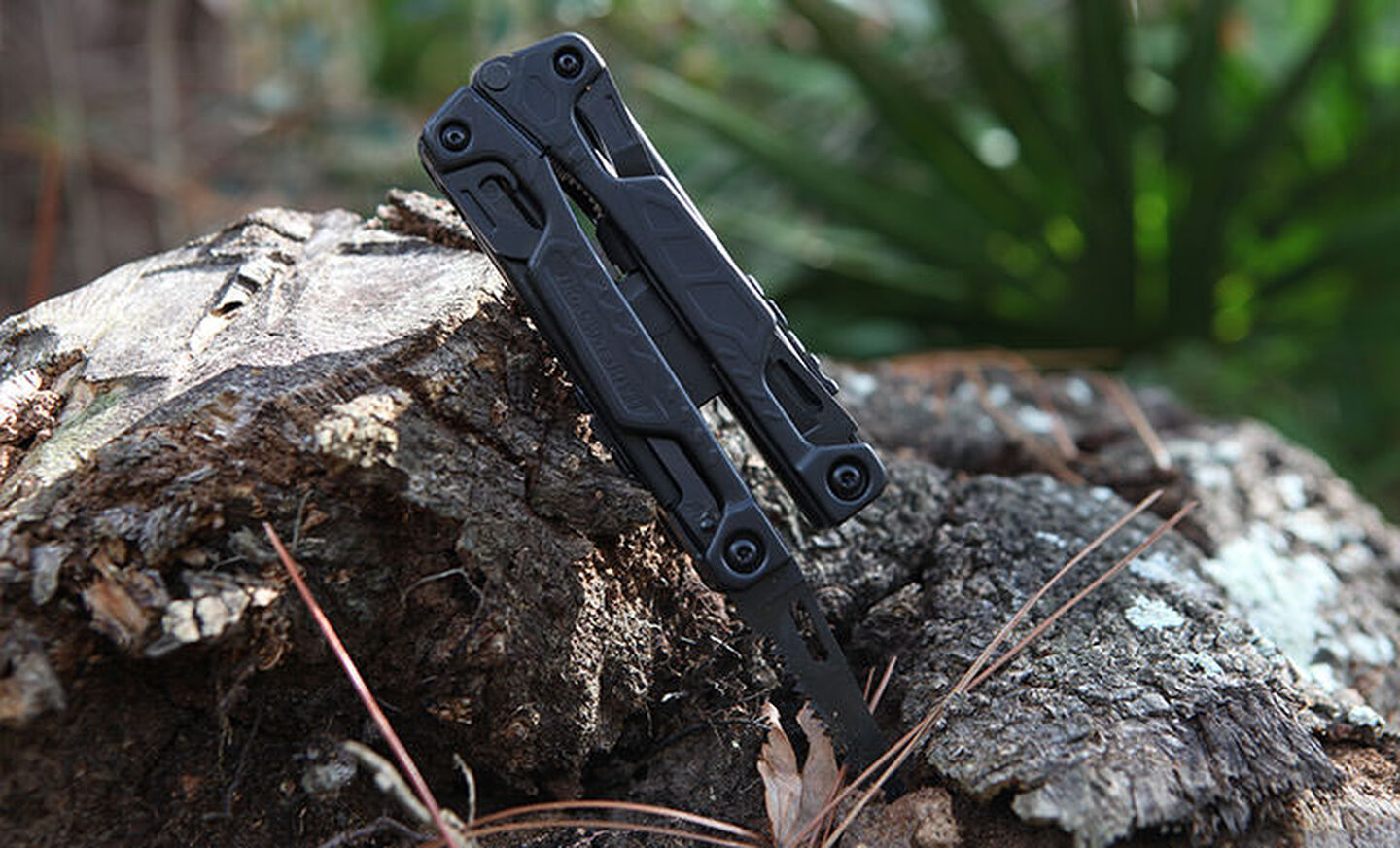 Black Leatherman OHT saw blade inside a piece of wood outdoors 