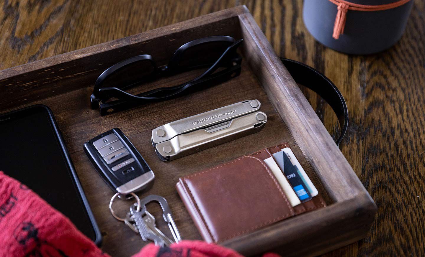 Wooden drawer with black sunglasses, Leatherman Bond, brown wallet, and black car key fob