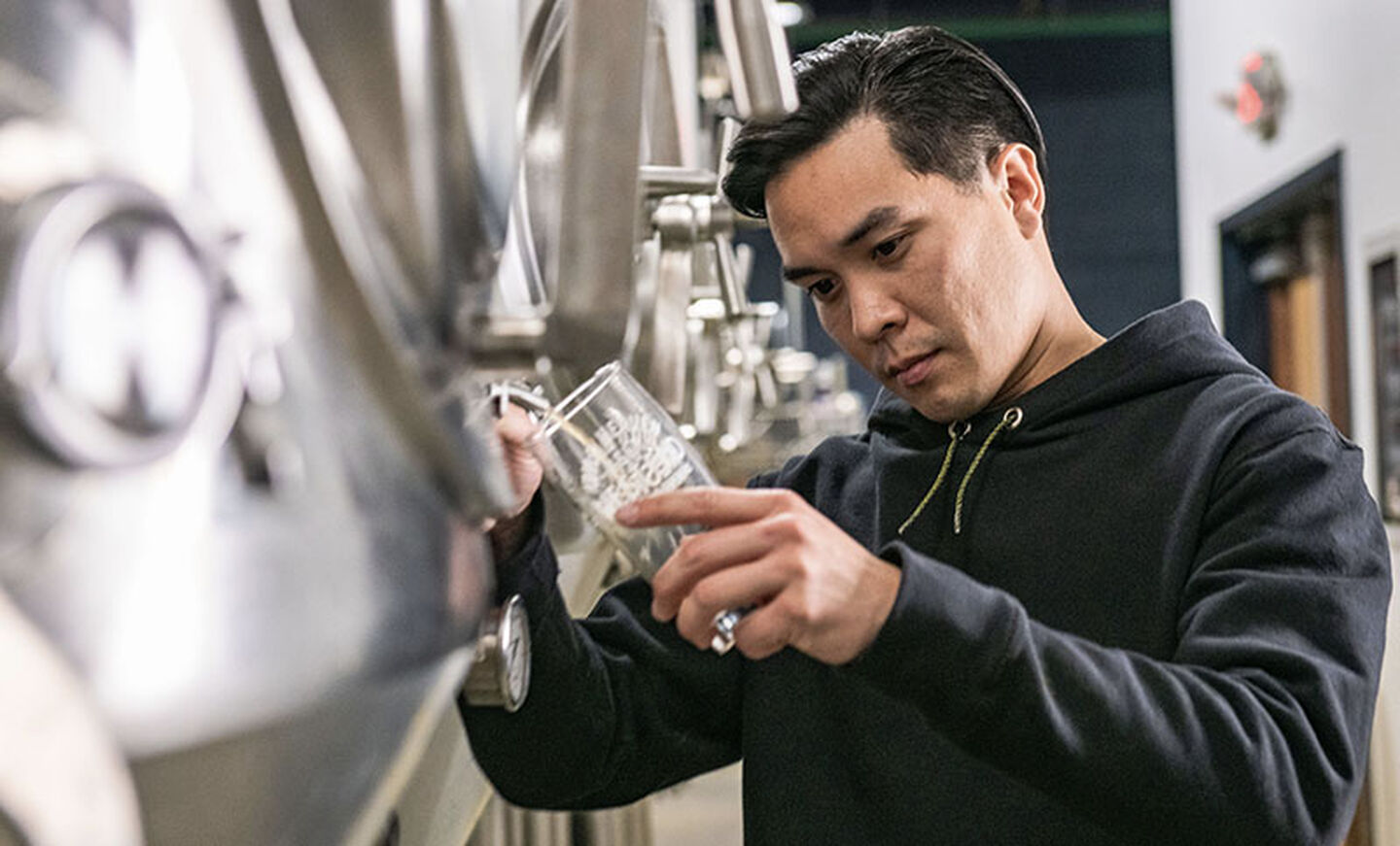 Brewer pours a cold beer while wearing Leatherman Basic Pullover Hoodie in black.