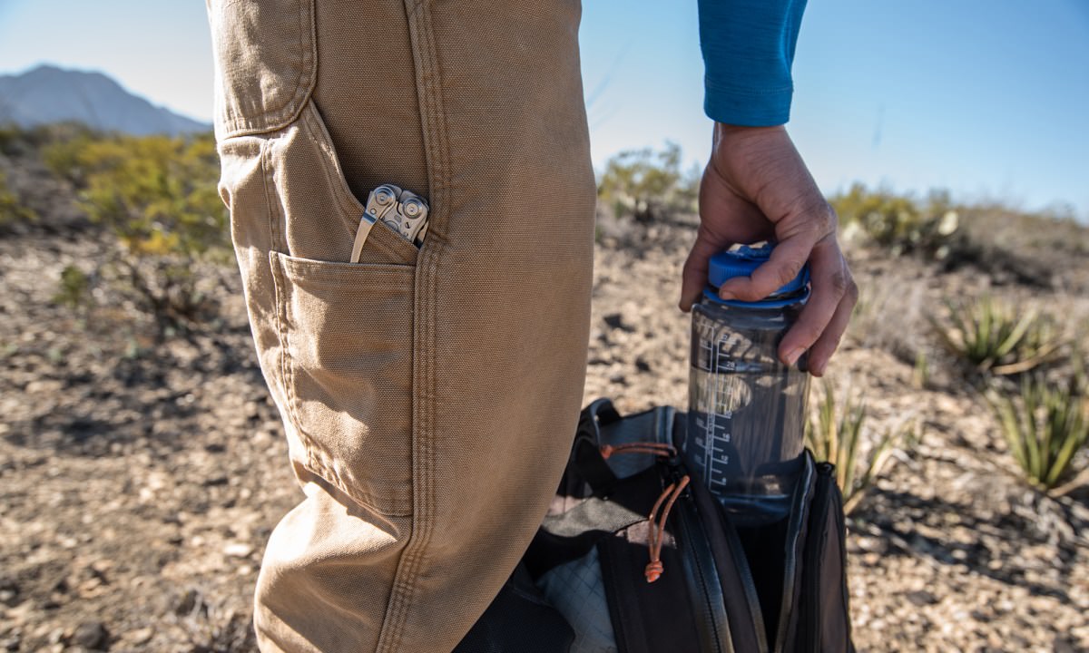 Hiker putting water in a pack with a Leatherman in their pocket
