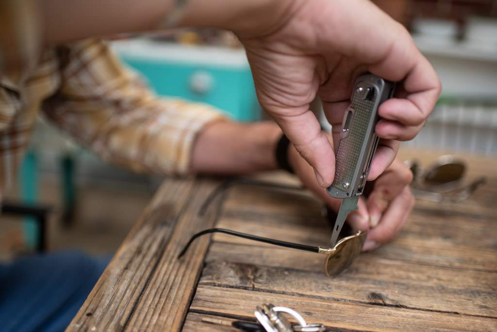 The Leatherman FREE T4 tightening a screw on a pair of sunglasses.