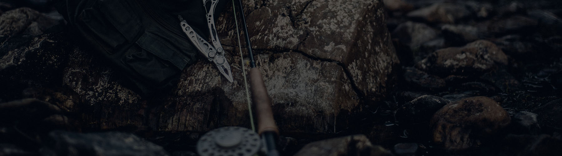 Bag, Leatherman Skeletool, Fishing Rod against rock