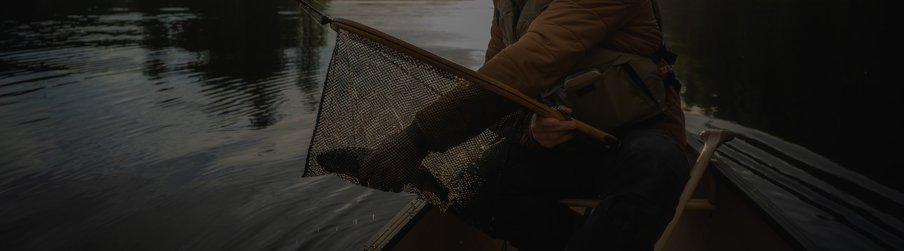 Man fishing in a canoe with a fish in his net