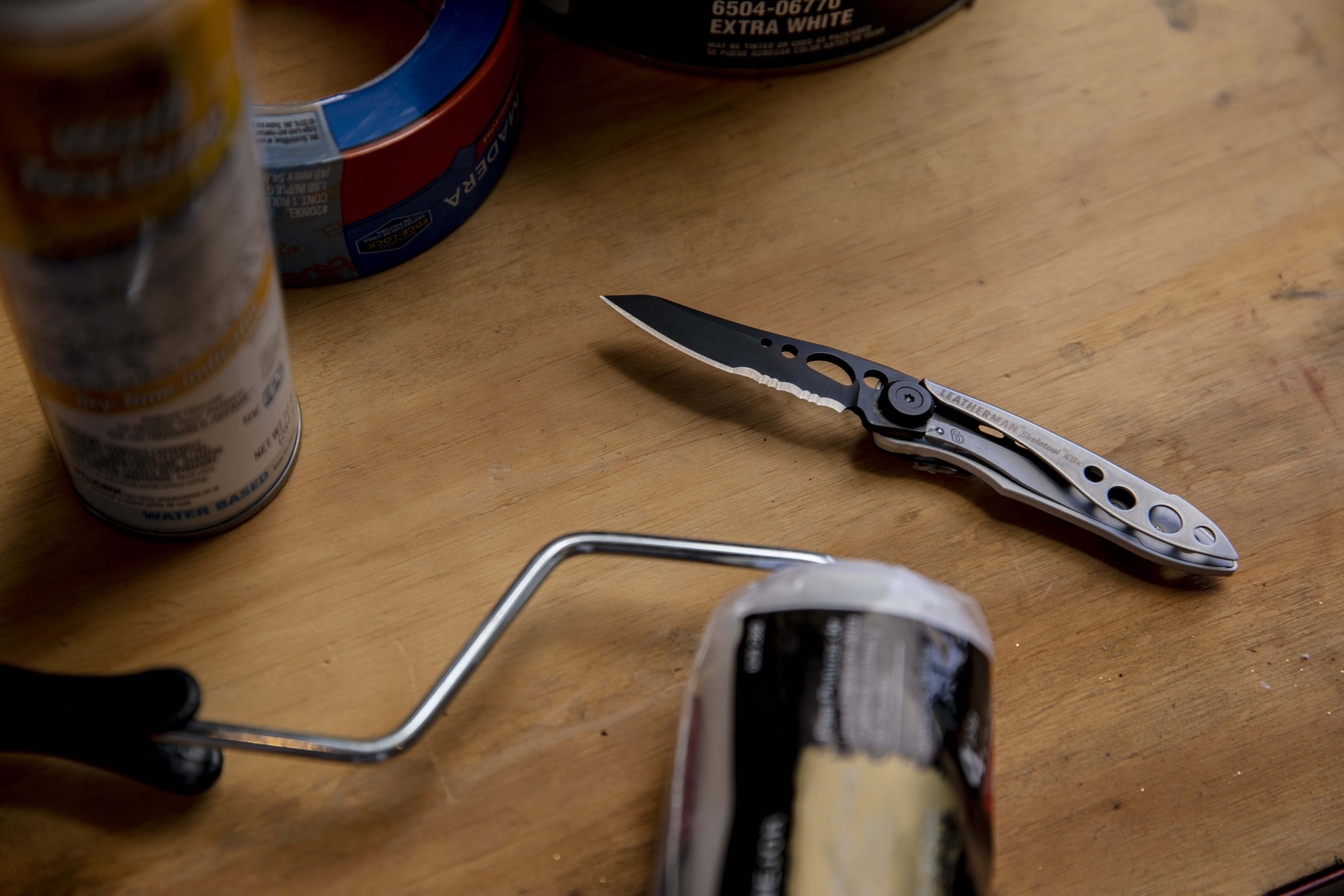 Black and Silver Skeletool KBX with open knife blade on wooden table