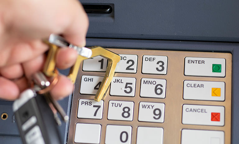 Clean Contact Carabiner aus Messing wird verwendet, um die Tasten an einem Geldautomaten zu drücken