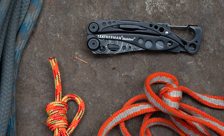 Leatherman Skeletool multi-tool, topo print, closed with rock climbing gear