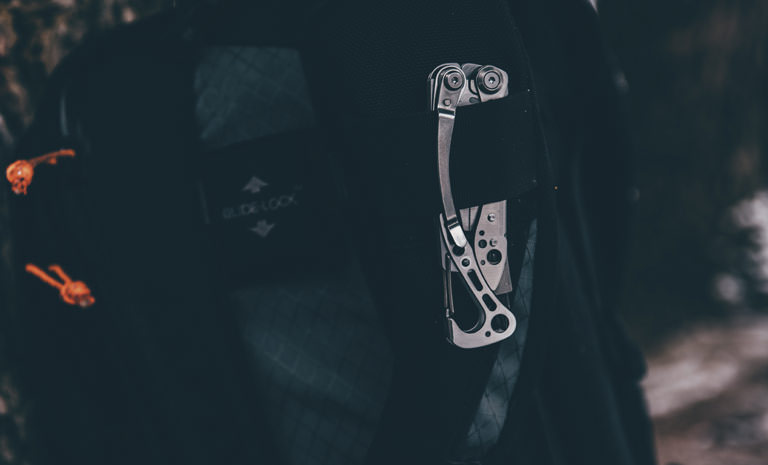 Leatherman stainless steel skeletool multi-tool clipped on backpack, used outdoors