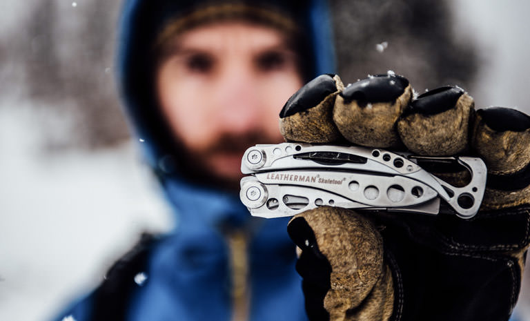 Leatherman stainless steel skeletool multi-tool in hand, used outdoors in snow
