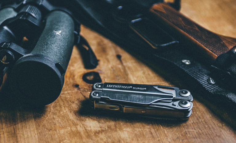 Leatherman surge multi-tool on wooden table, next to hunting gear